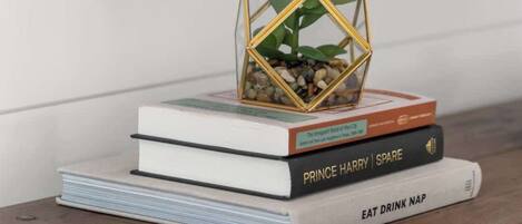 A stack of books with a small plant in a geometric container on top.