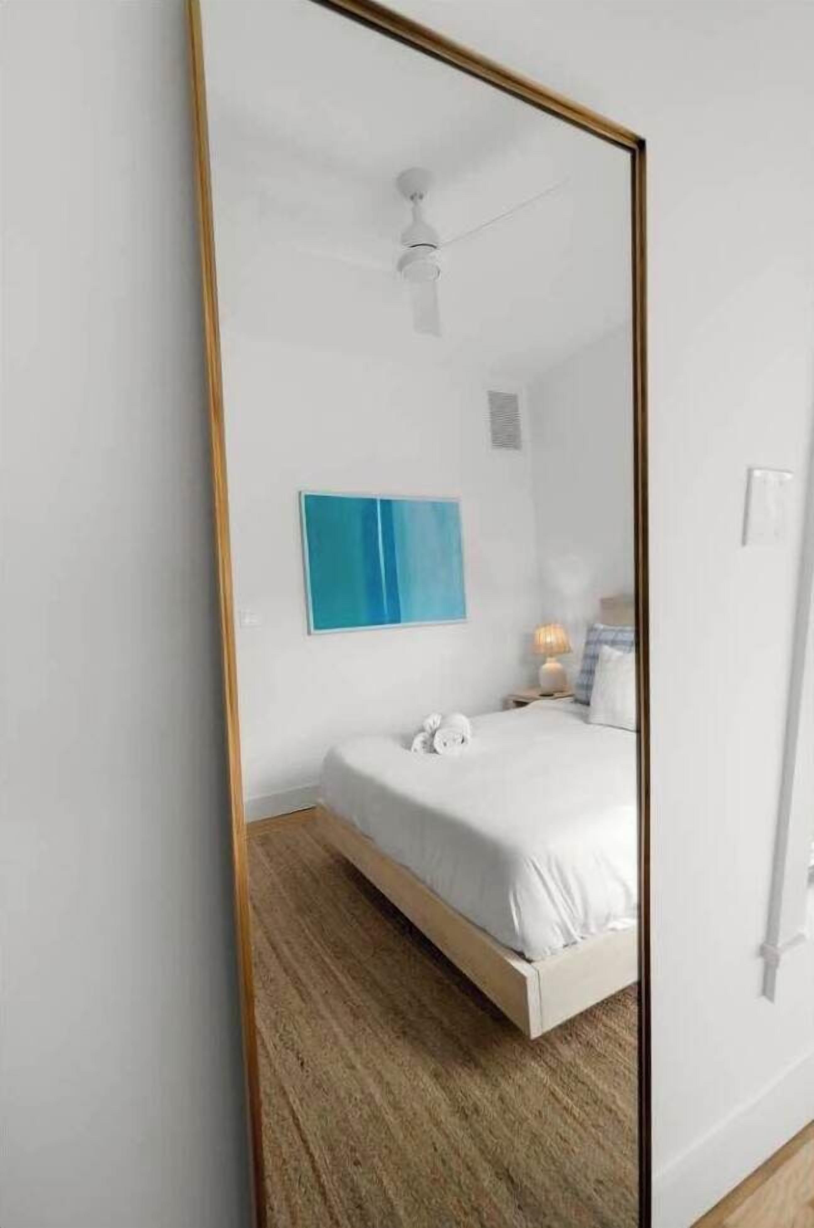 A bedroom with a bed, a blue painting, a nightstand, and a ceiling fan.