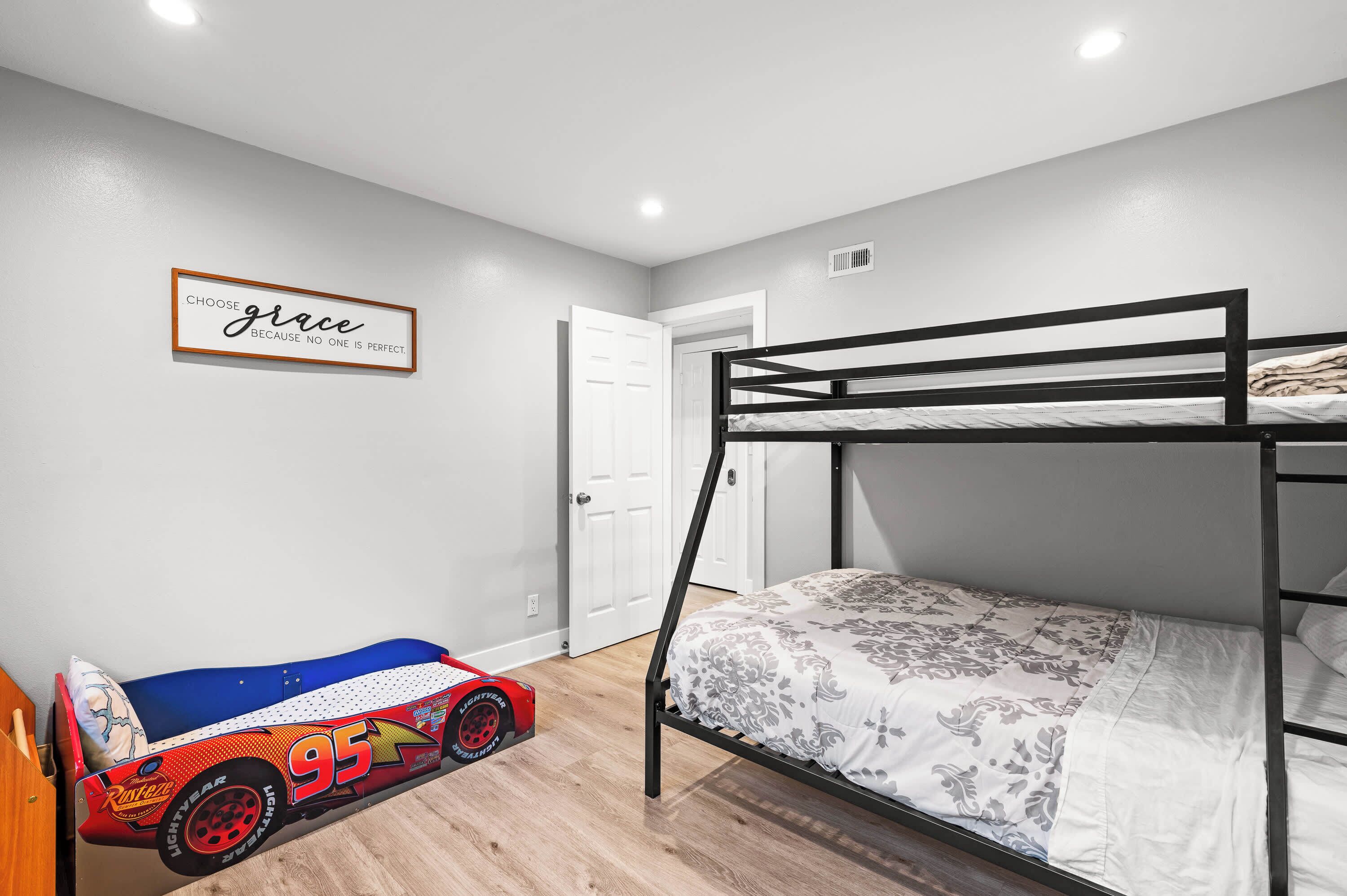 Een slaapkamer met een stapelbed, een raceauto speelgoed en een motiverende quote op de muur.