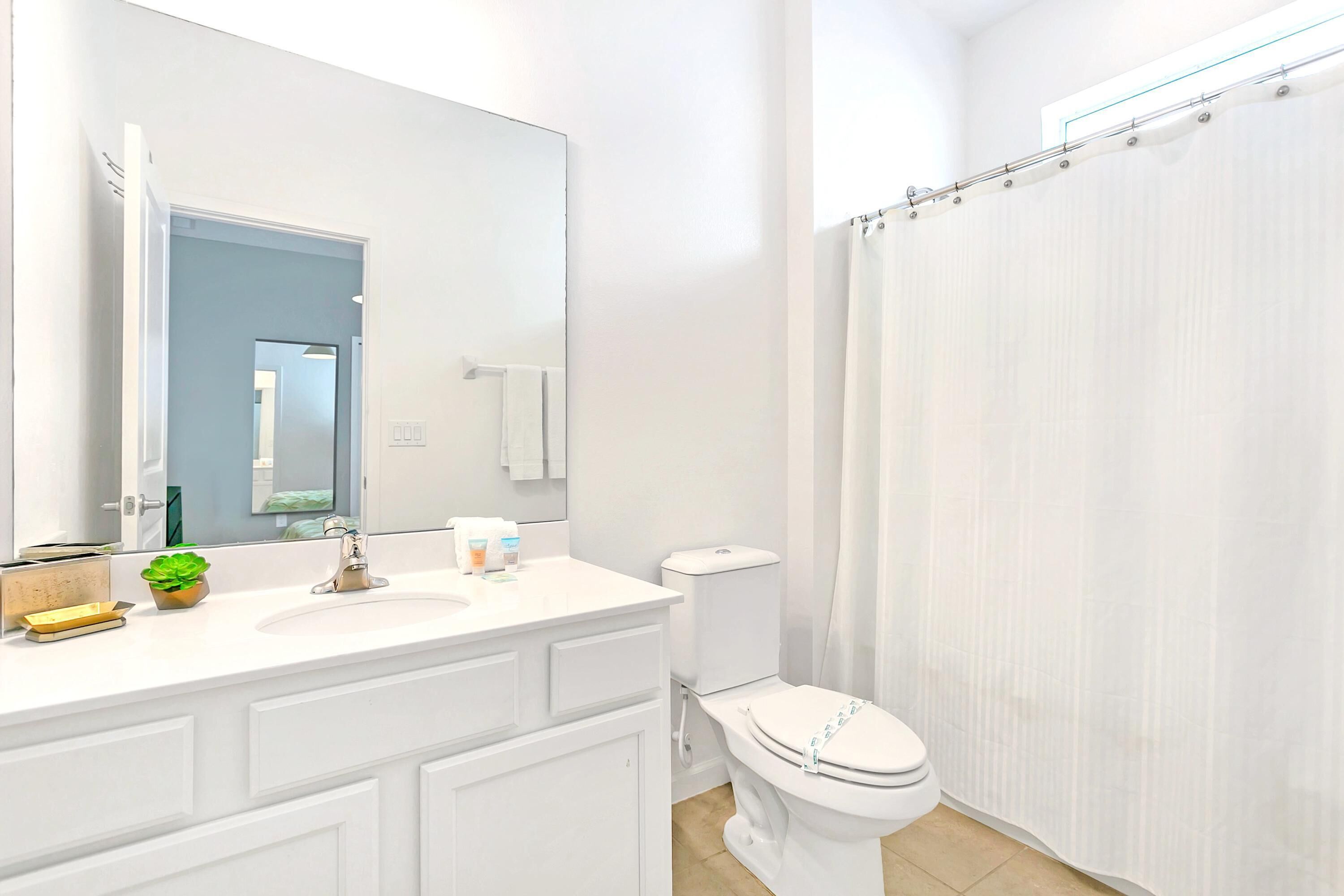 A modern bathroom with a white sink, mirror, and toilet.