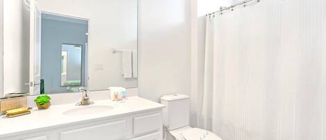 A modern bathroom with a white sink, mirror, and toilet.
