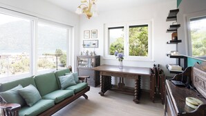 A spacious living room with a green sofa, a wooden dining table, and a piano.