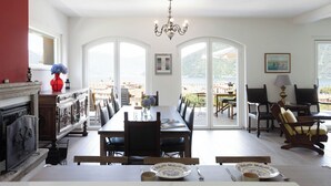 A dining area with a long table, chairs, and a chandelier.
