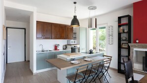 A modern kitchen with a central island, wooden cabinets, and a dining area with a black chair.