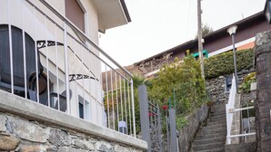 Eine Treppe aus Stein führt zu einem Gebäude, begleitet von einem Metallgeländer und einer Steinmauer.