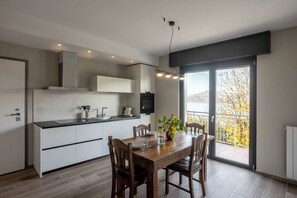 Eine moderne Küche mit weißen Schränken, einem Holzespeisetisch und Blick auf einen Balkon mit Herbstlaub.