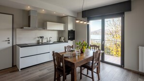 Eine moderne Küche mit weißen Schränken, einem Holzespeisetisch und einem großen Fenster mit Blick auf einen Balkon.