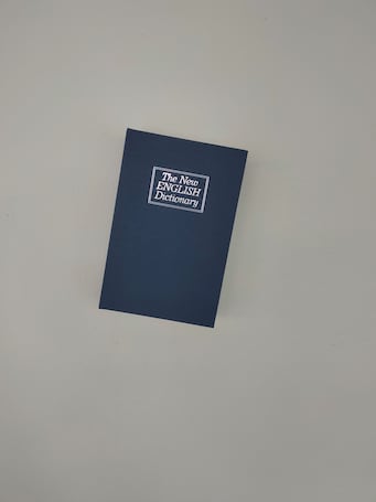 A closed book titled "The New English Dictionary" on a plain background.