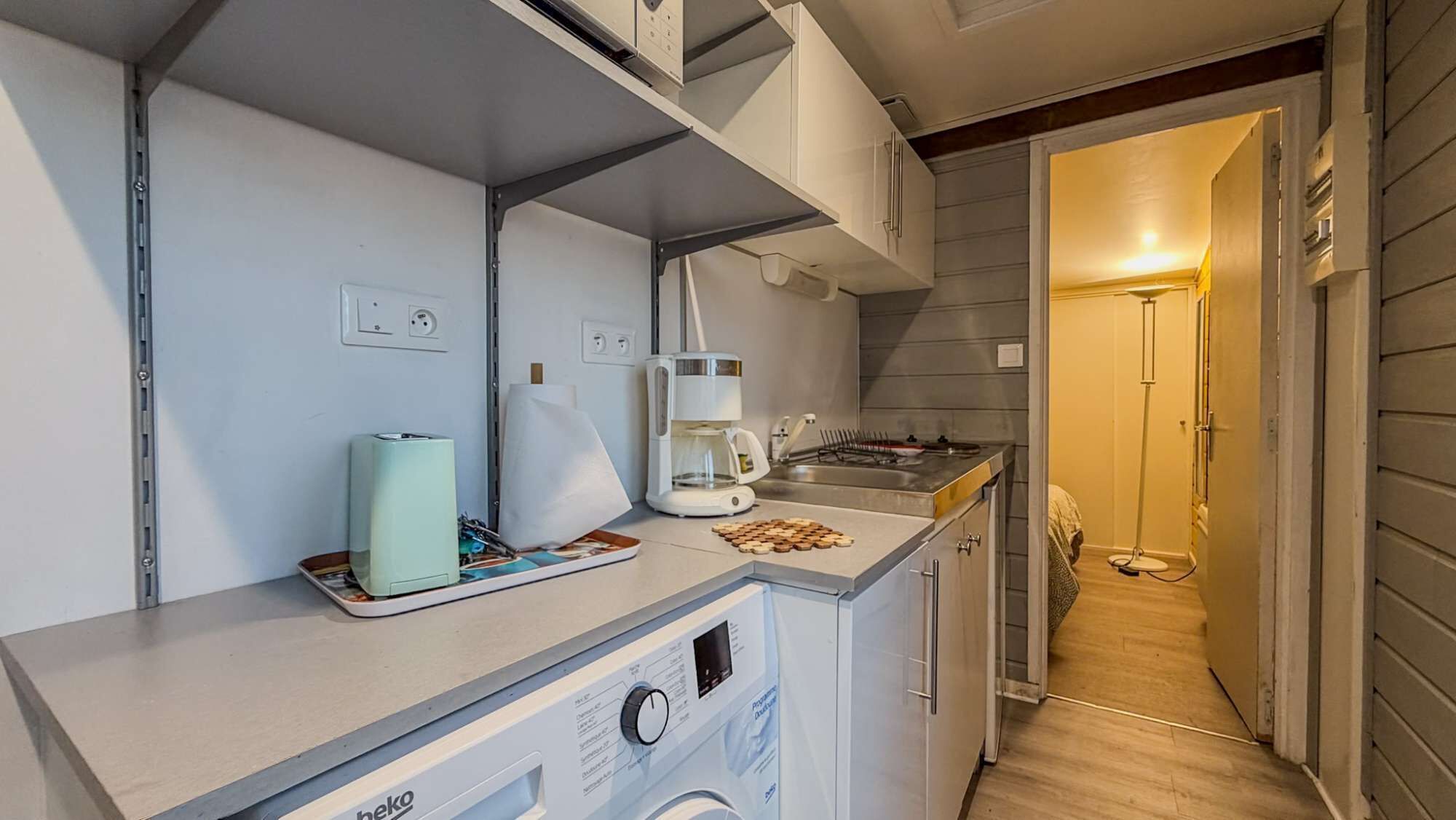Een kleine keuken met een koffiezetapparaat, een broodrooster en een wasmachine.
