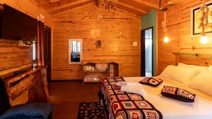 A cozy wooden cabin room with a bed, a bench, a small table, and a chandelier. - Hospedagem Rural Recanto do Riacho (Urubici)