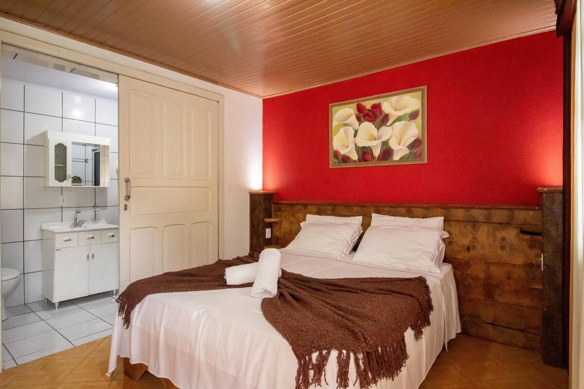 A bedroom with a wooden headboard, a white bedspread, and a brown throw blanket.