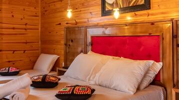 Quarto de cabana de madeira com cama, cabeceira vermelha e quadro com flores na parede.