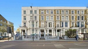 Fila de casas adosadas con entrada central, pequeño balcón y un paso de peatones enfrente.