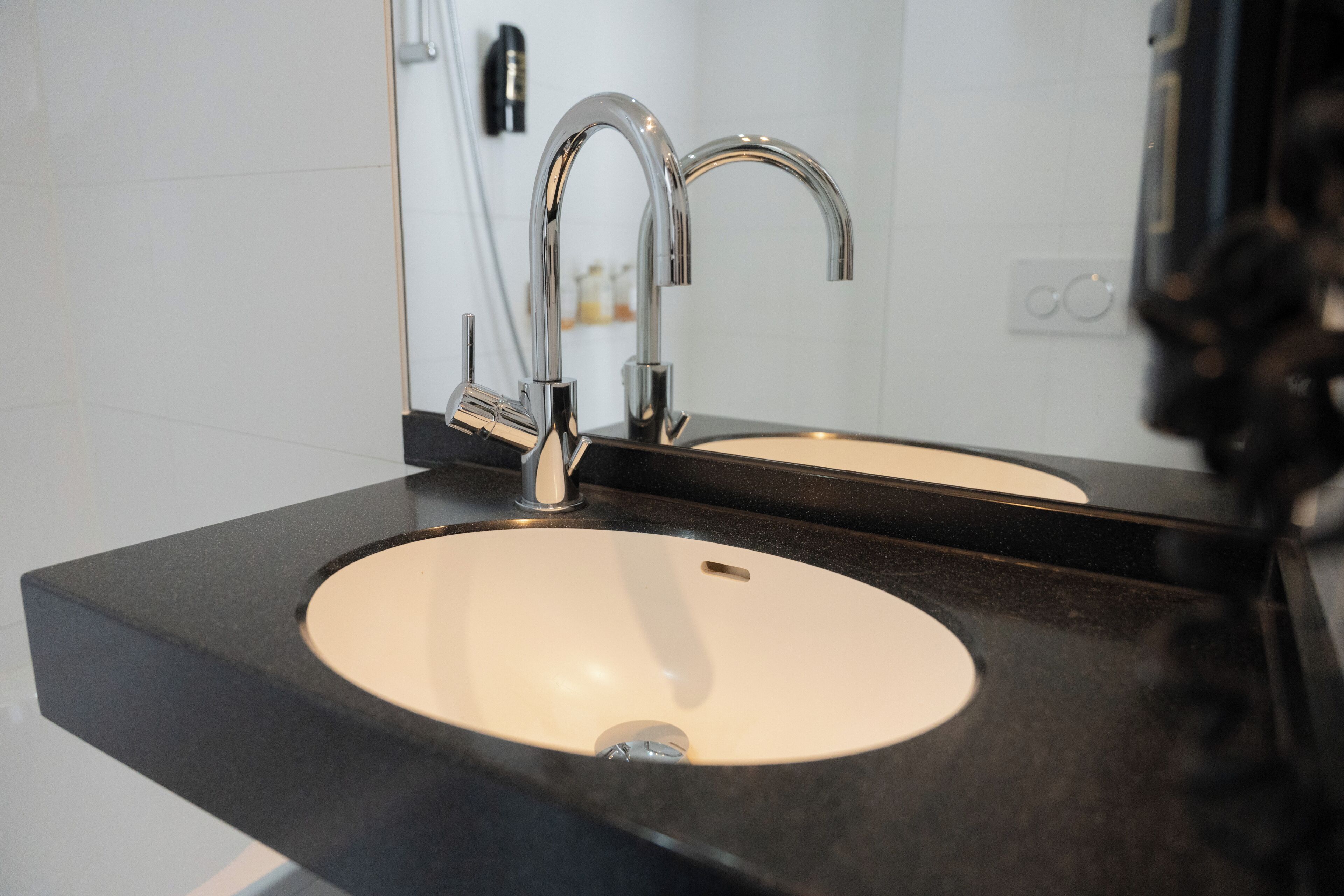 A bathroom with a double sink, a mirror, and a faucet.