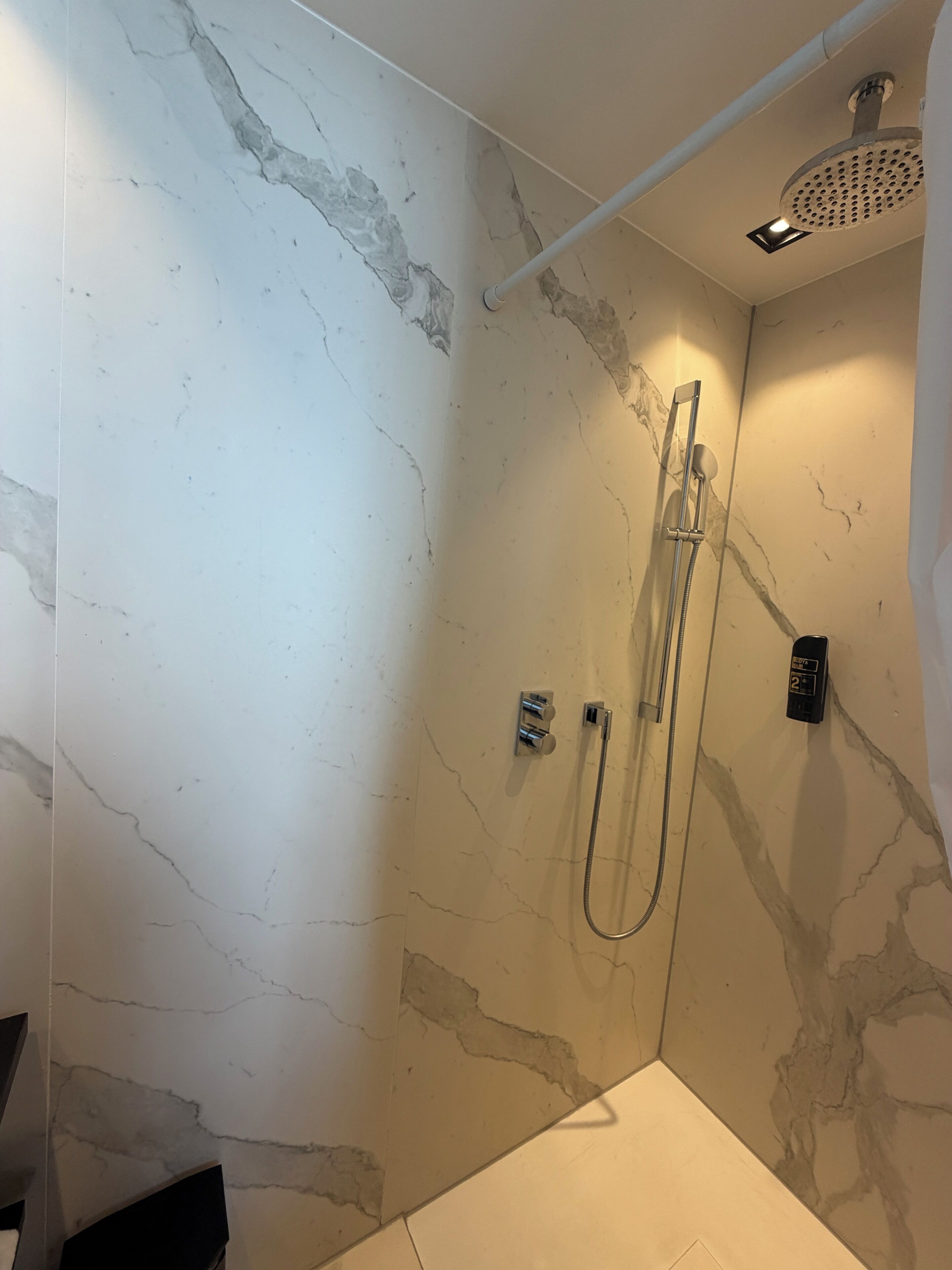 Une douche équipée d’un pommeau de douche à main, d’un panneau de commande mural et d’un pommeau de douche à main.