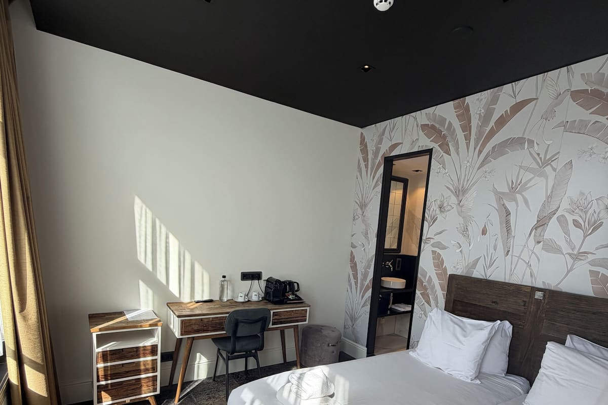 Une chambre d’hôtel avec un grand lit, un bureau, une chaise et une armoire.