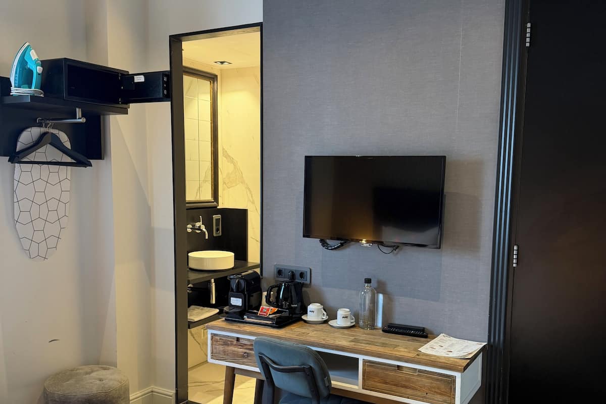 Une chambre d’hôtel équipée d’un lit, d’un bureau avec une télévision, d’un miroir et d’une machine à café.
