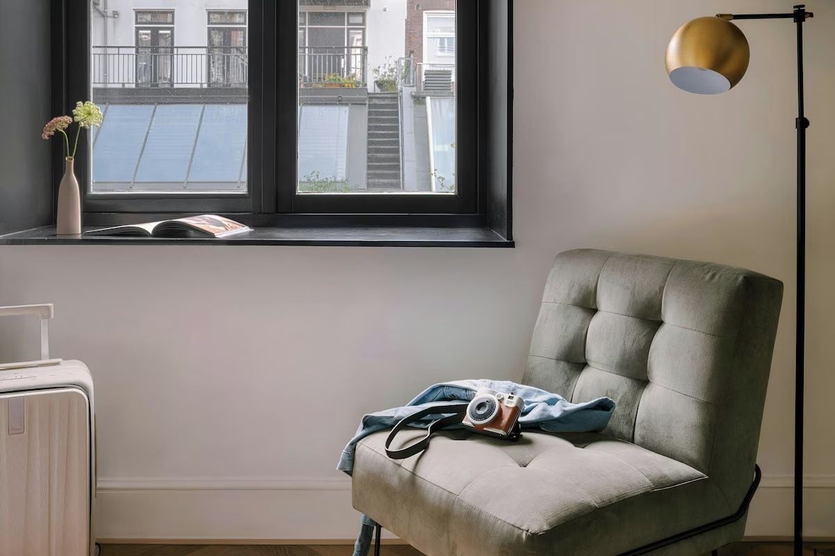 A room with a window, a chair, a lamp, and a radiator.