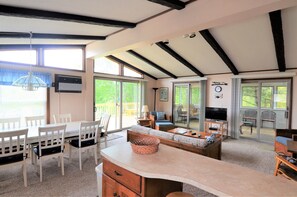 A spacious living area with a large window, a dining table, chairs, a sofa, and a television. - "OLD SCHOOL" REHOBOTH HOME IN NORTH SHORES - 3 FARVIEW (Rehoboth Beach)