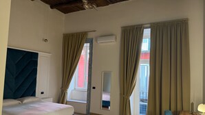 A bedroom with a bed, a wooden desk, and a window with curtains. - Chiaia Lifestyle (Naples)