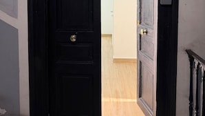 A black door leading to a room with wooden flooring and a white wall. - Chiaia Lifestyle (Naples)