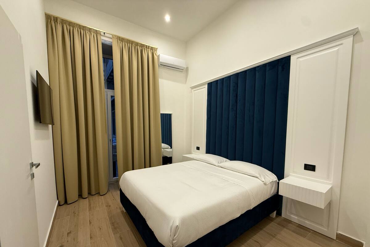 A hotel room with a bed, a television, a wardrobe, and a bathroom.