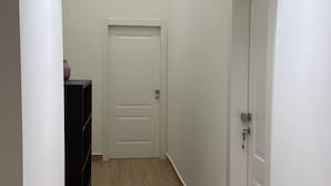 A narrow hallway with a wooden floor, white walls, and a door at the end. - Chiaia Lifestyle (Naples)