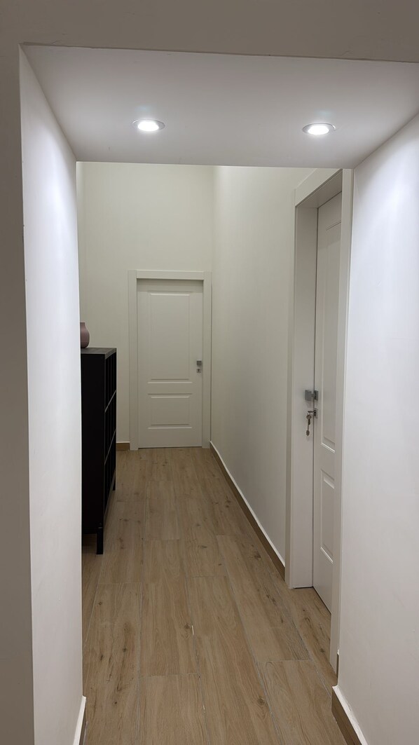 A narrow hallway with a wooden floor, white walls, and a door at the end. - Chiaia Lifestyle (Naples)