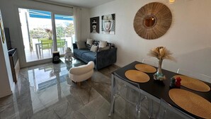 Un salon moderne avec un canapé, une table à manger agrémentée de sets de table et un élément décoratif mural.