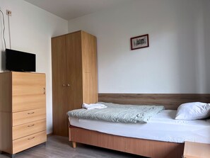 A bedroom with a wooden bed, a wooden wardrobe, and a television on top of the wardrobe. - DW Belmara (Kołobrzeg)