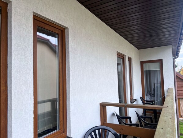 A covered outdoor area with a wooden bench and chairs, large windows, and a ceiling with wooden beams. - DW Belmara (Kołobrzeg)