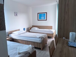 A hotel room with two beds, a desk, a chair, a lamp, and a framed picture on the wall. - DW Belmara (Kołobrzeg)