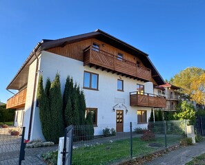 A two-story house with a balcony, a wooden facade, and a fenced yard. - DW Belmara (Kołobrzeg)