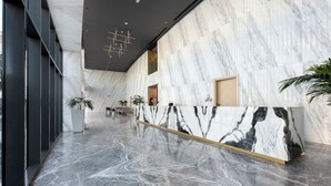 A spacious lobby with a marble reception desk, large windows, and modern lighting fixtures. - Modern 1BR with Pool and Gym Al Jaddaf (Dubai)