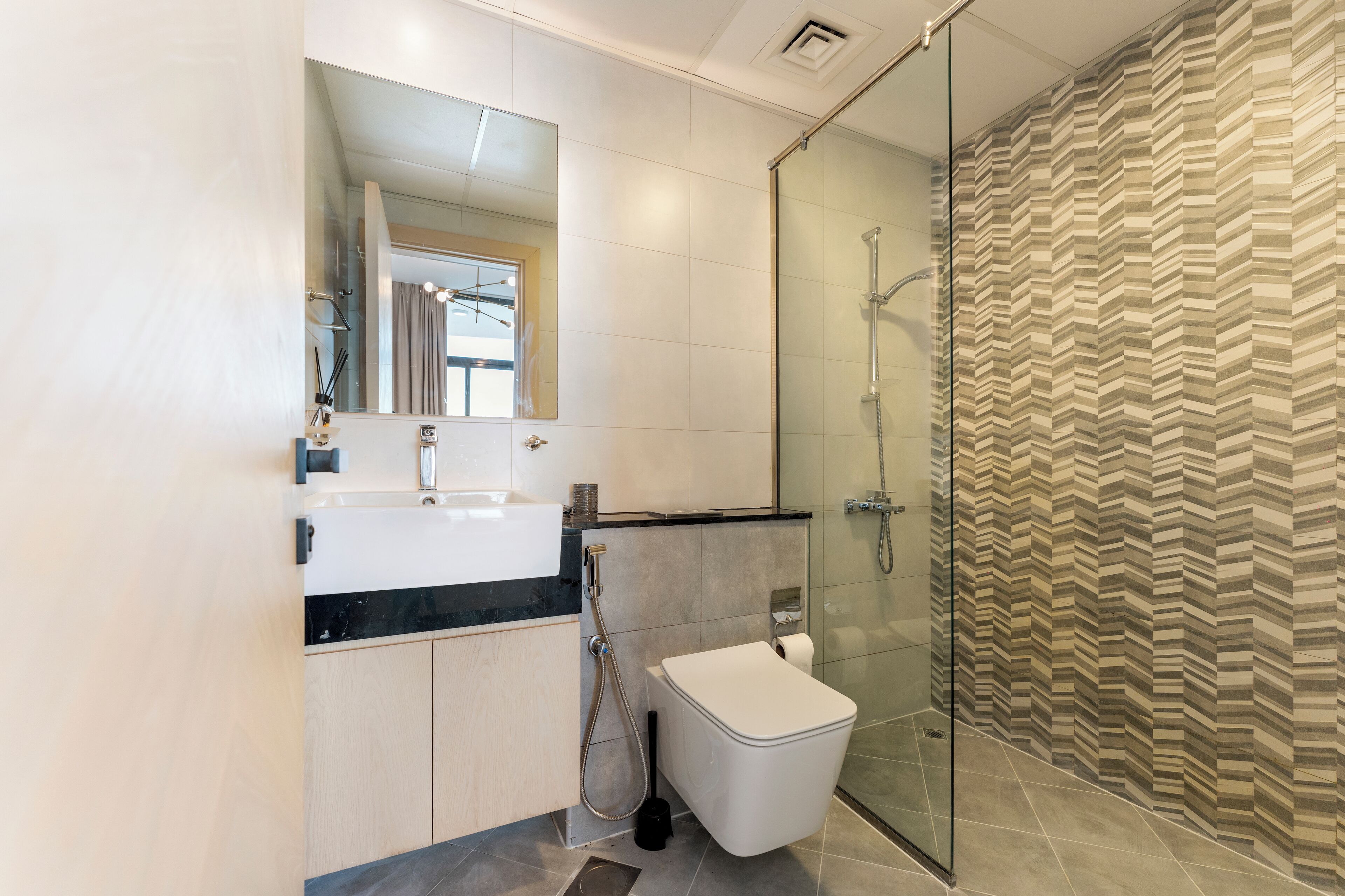 A modern bathroom with a glass shower enclosure, a white toilet, and a vanity with a mirror.