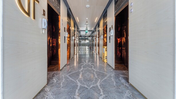 A hotel corridor with a marble floor, wooden paneling, and a large illuminated 'G' sign. - Modern 1BR with Pool and Gym Al Jaddaf (Dubai)