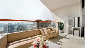 A modern balcony with a sofa, two armchairs, a small table with a floral arrangement, and a potted plant. - Modern 1BR with Pool and Gym Al Jaddaf (Dubai)