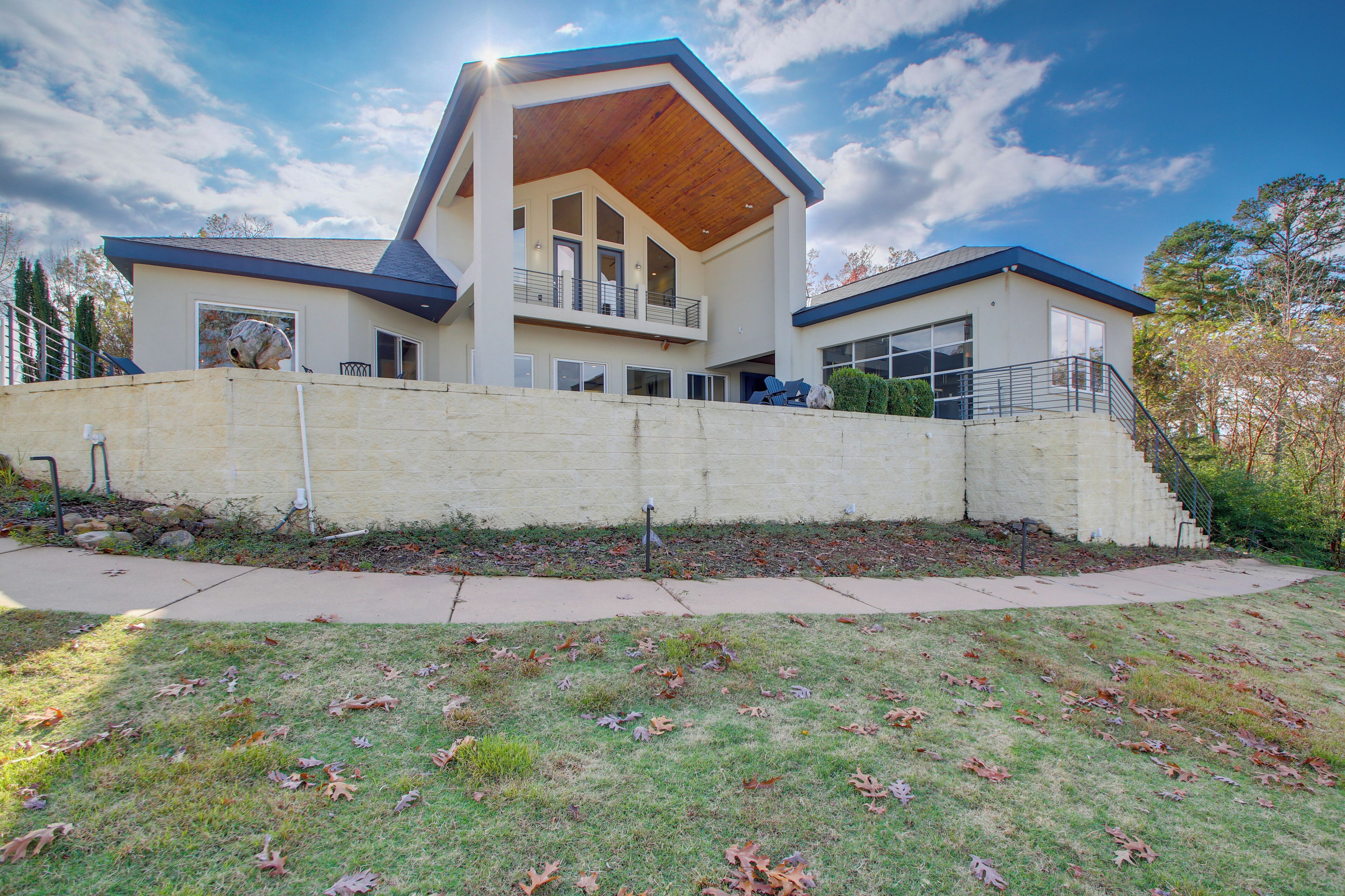 A modern two-story house with a flat roof, large windows, and a covered balcony.