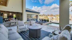 An outdoor patio area with seating, a pool, and a view of a lake and houses in the background. - Private Pool & Slip: Luxury Lake Hamilton Home! (Hot Springs)