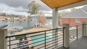 A view from a balcony overlooking a swimming pool, with a lake and buildings in the background. - Private Pool & Slip: Luxury Lake Hamilton Home! (Hot Springs)