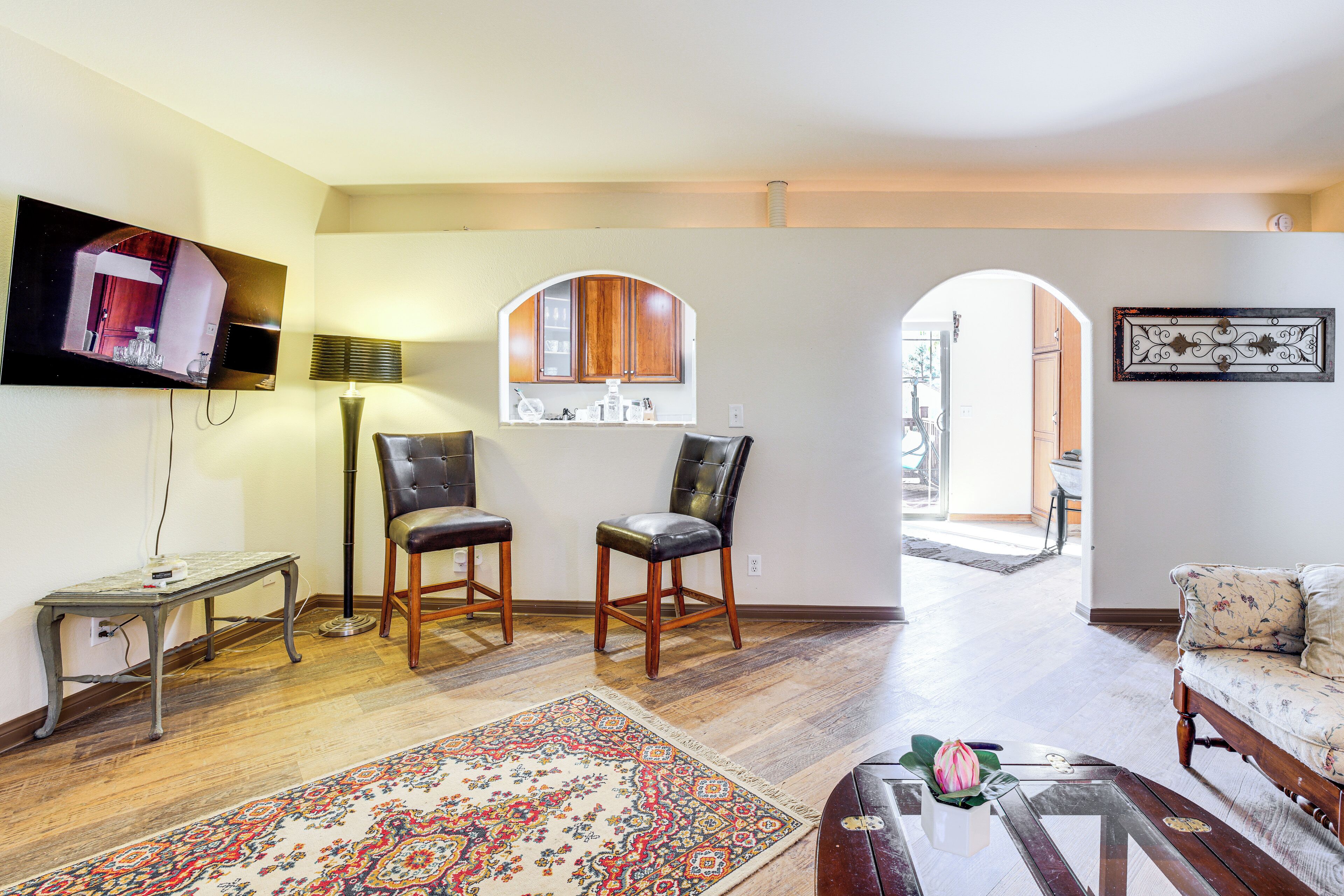 A living room with a television, two leather chairs, a sofa, a coffee table, and a rug.