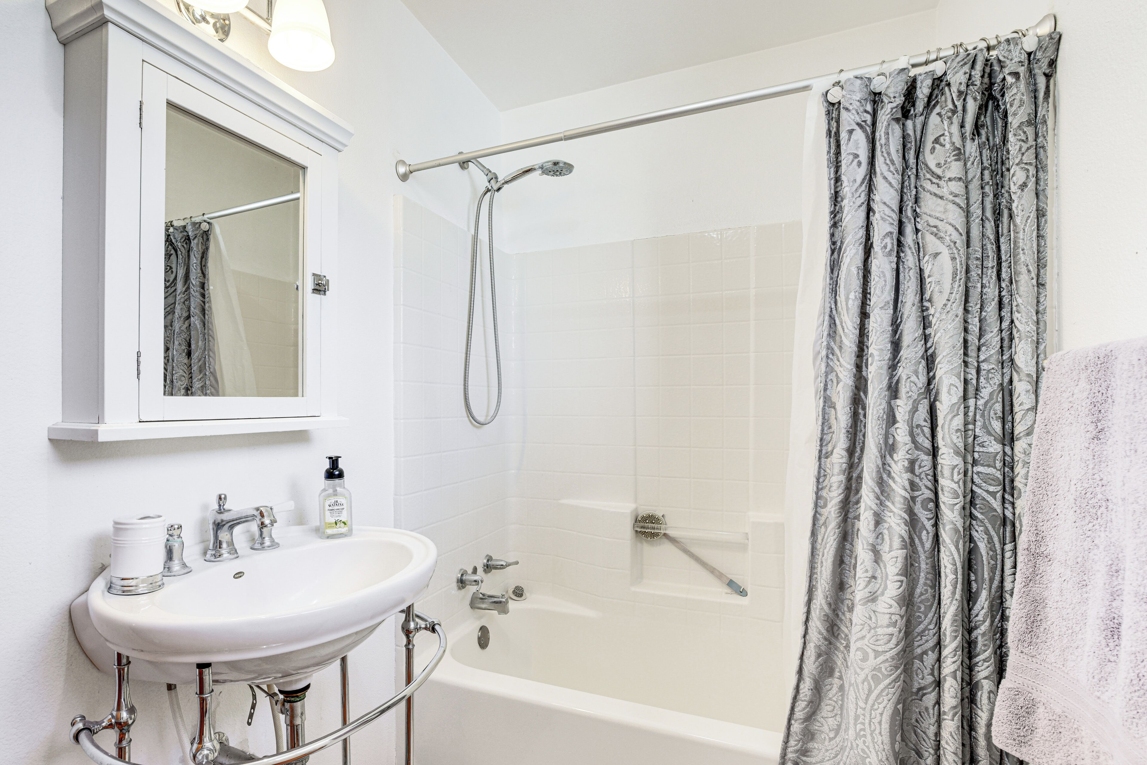 A bathroom with a white sink, mirror, and shower area.