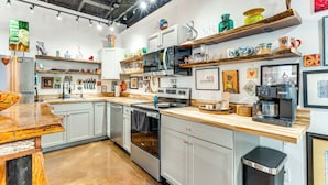 Een moderne keuken met witte kasten, roestvrijstalen apparatuur en houten aanrechtbladen.