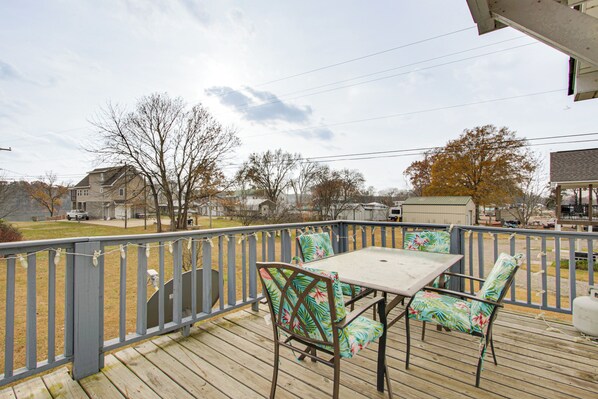 A wooden deck with a table and chairs, overlooking a residential area with houses and trees. - Near Tennessee River! Pet-friendly Family Cottage! (Savannah)