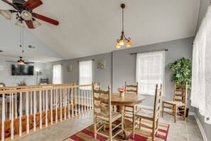 A dining area with a round table, wooden chairs, a red and beige striped rug, a ceiling fan, and a hanging light fixture. - Near Tennessee River! Pet-friendly Family Cottage! (Savannah)