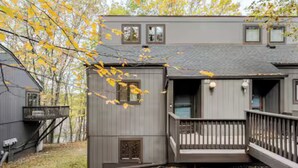 A two-story cabin with a deck and a small porch. - Ski-in/ski-out Camelback Mtn Retreat w/ Hot Tub (Tannersville)