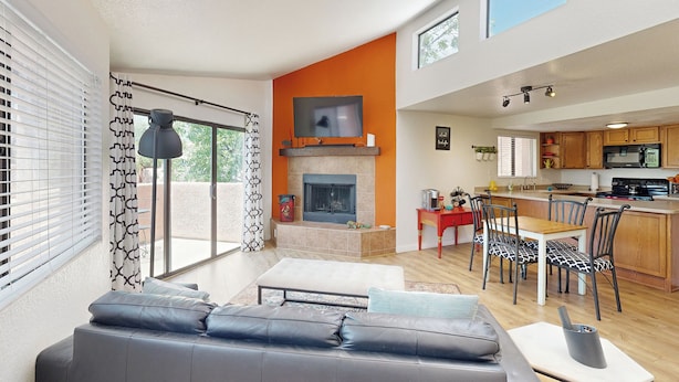 A modern living room with a fireplace, a dining area, and a kitchen. - 1 BR Condo in Tucson, Mountain Views (Tucson)