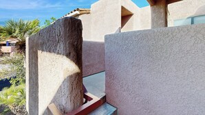 A modern building with a textured facade, a clear sky, and some greenery in the background. - 1 BR Condo in Tucson, Mountain Views (Tucson)
