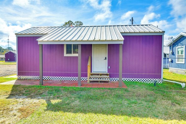 Un petit bâtiment d’un seul étage, à la façade violette et à la porte blanche.