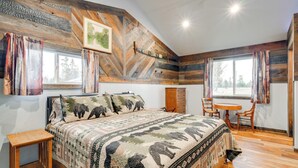Un dormitorio con una cama grande, un cabecero de madera, una mesita pequeña y dos sillas.
